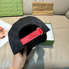 Black GG-pattern baseball cap with red logo patch and curved brim opening visible.