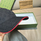 Black GG-pattern baseball cap close-up showing curved brim with red underside trim.