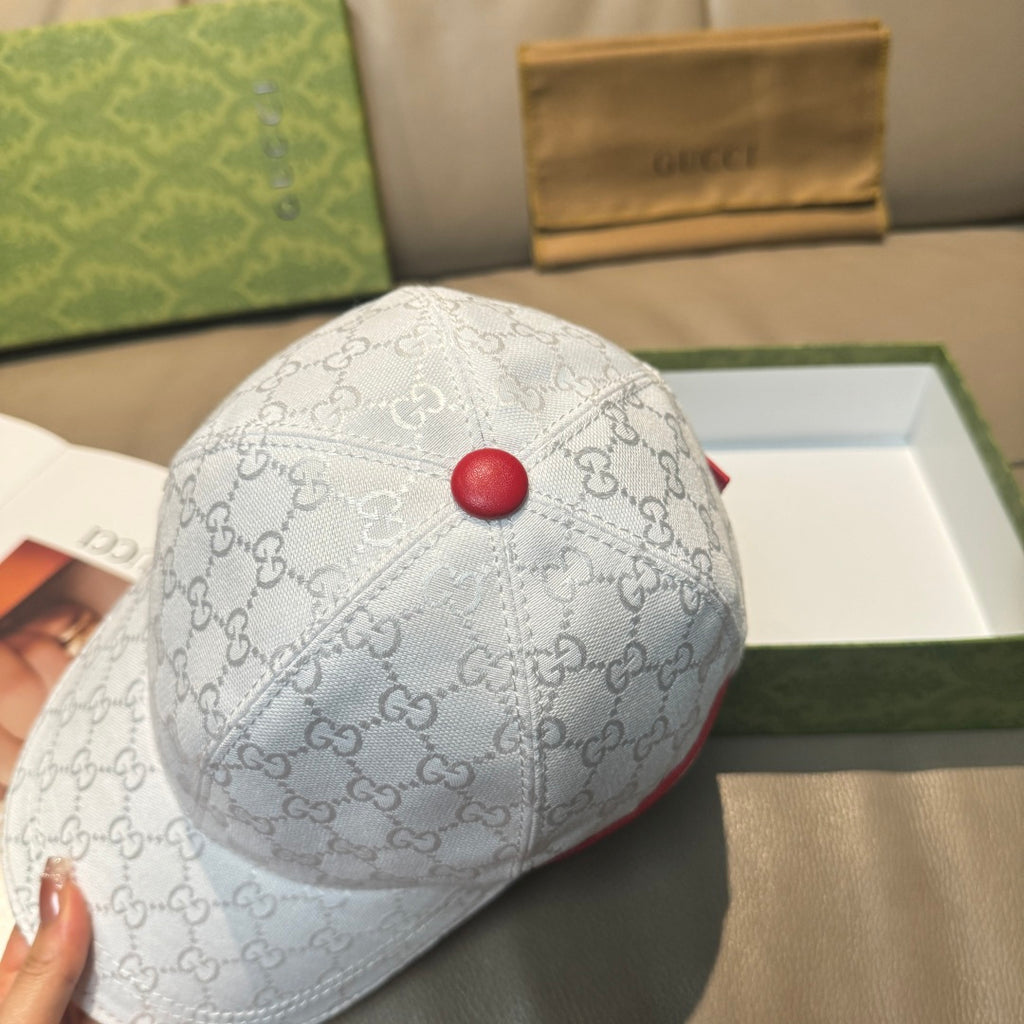 Gucci cap in light color with GG monogram pattern and red button on top.