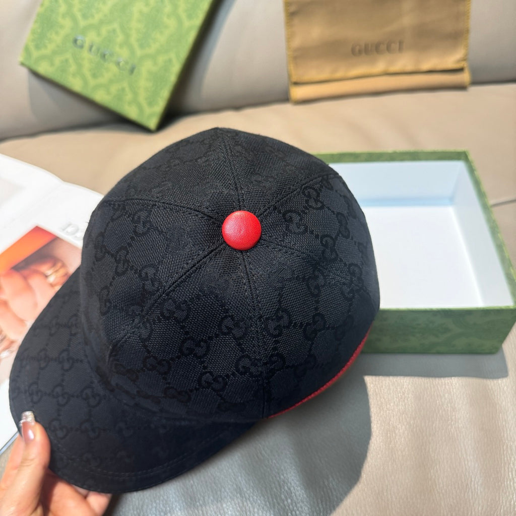 Black GG-pattern baseball cap with round red button on top and curved brim.