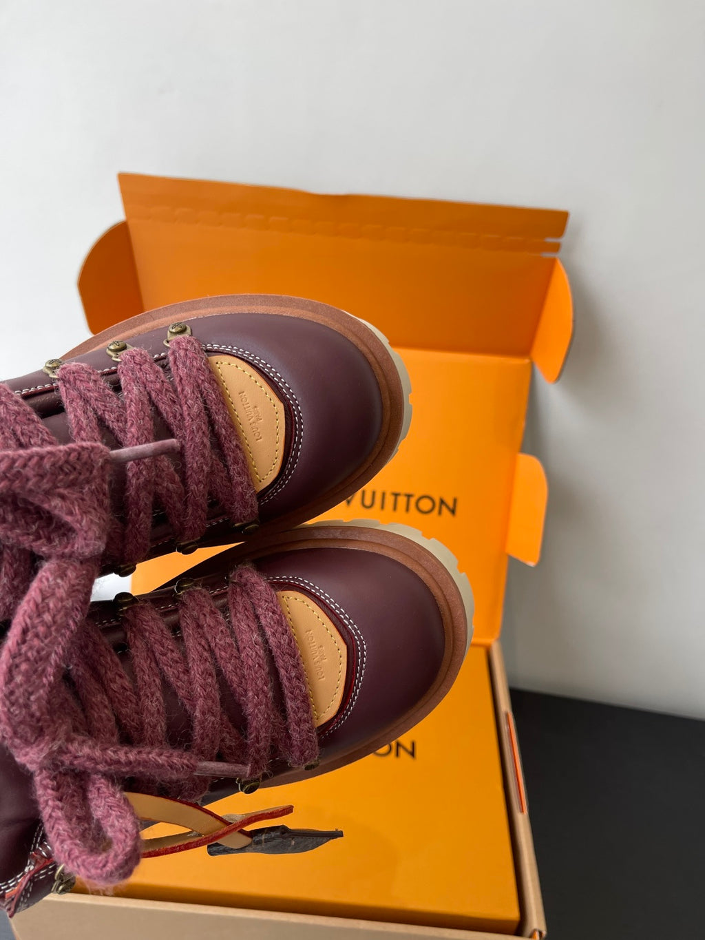 Louis Vuitton women's sneaker close-up: dark purple laces over tan-lined eyelets