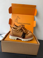 Women’s Louis Vuitton tan lace-up sneakers, side view with textured sole.