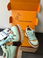 Women's mint sneakers with brown strap details and blue laces, in box