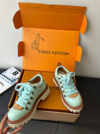 Women's mint sneakers with blue laces and brown trim, shown in box