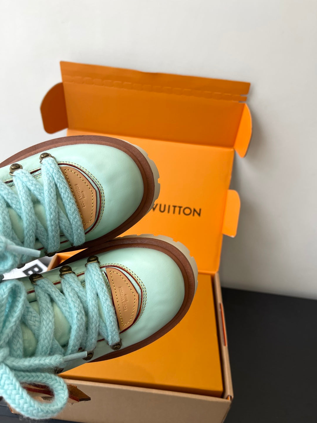 Women's mint sneakers with blue laces, brown trim, side view in box
