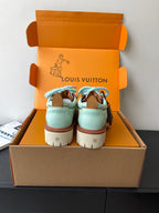 Pair of women's mint sneakers with blue laces and brown trim, back view in box