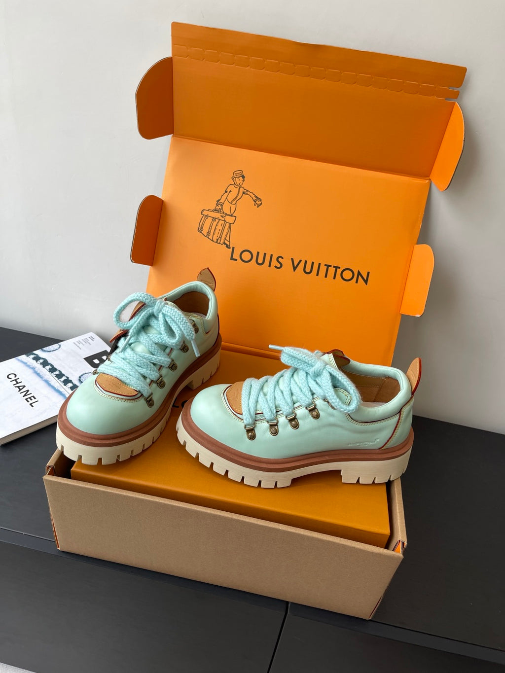 Women's mint sneakers with blue laces and treaded sole, angled in box