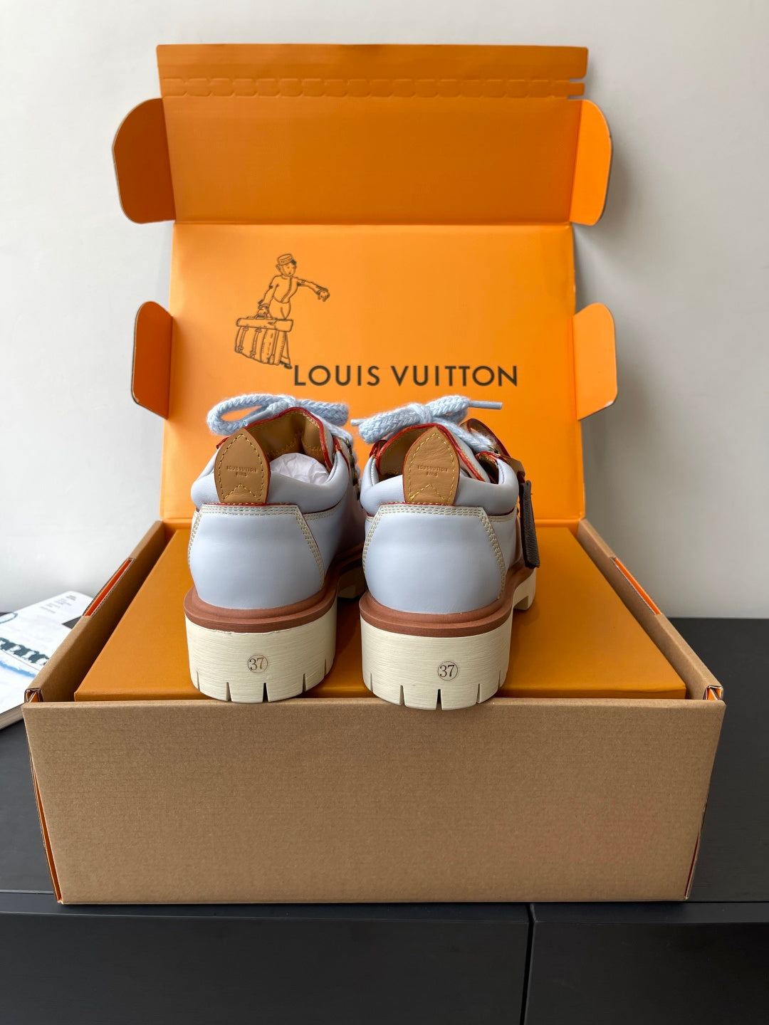 Women's white sneakers with blue laces and brown accents, rear view