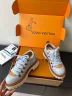 Women's white sneakers with blue laces and brown-trimmed toe, chunky sole