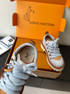 Women's white sneaker with blue laces, brown logo detail near tongue