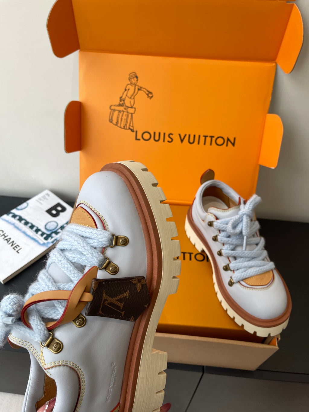 Women's white sneakers with blue laces, tan trim, side metal D-ring hardware