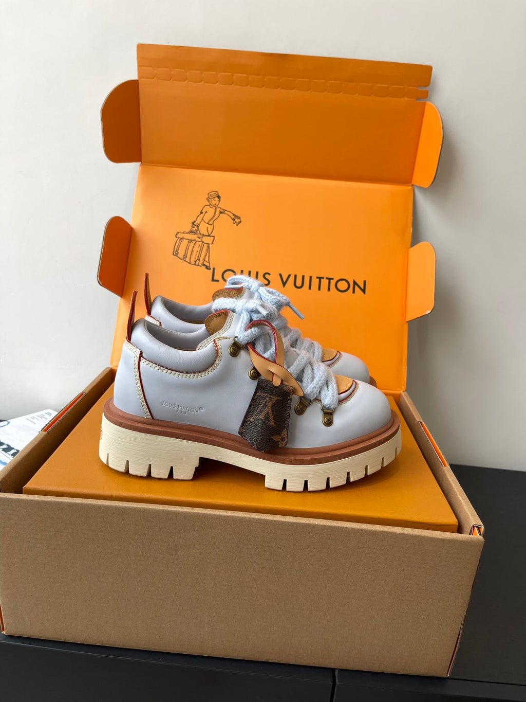 Women's white sneakers with blue laces, brown trim, rubber lug sole