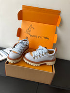Women's white sneakers with blue laces, brown trim, thick lug sole