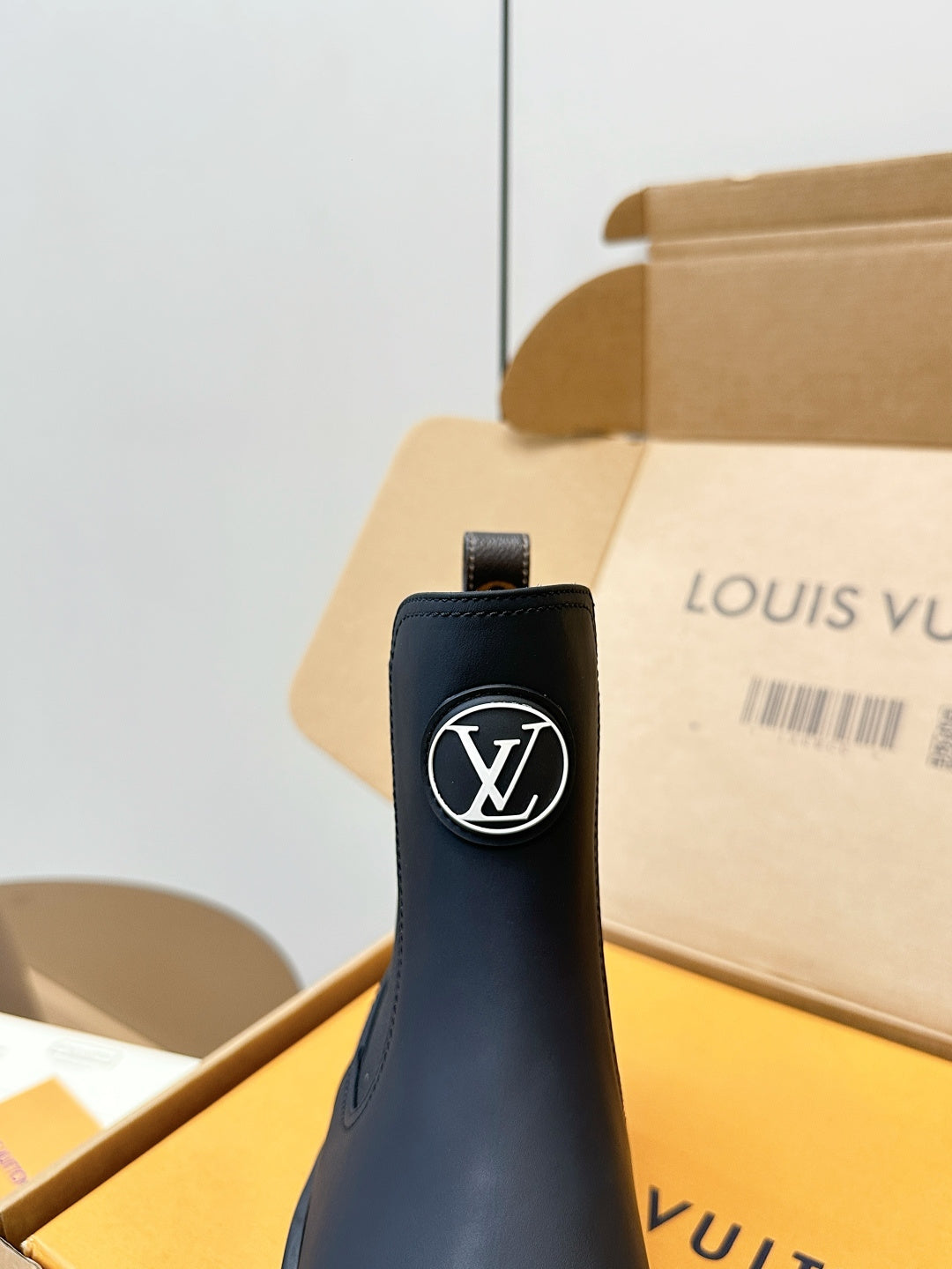 Louis Vuitton logo on dark navy ankle boot with pull tab and elastic gore