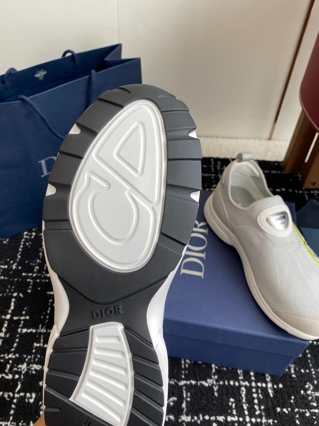 White slip-on sneaker outsole view on dark tread, with Dior logo on shoe