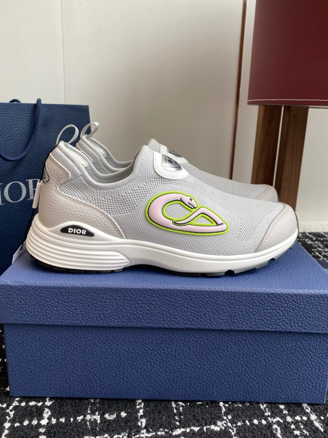 White low-top slip-on sneakers with neon-green logo on side, Dior branding