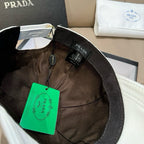 Black baseball cap with Prada label and attached green price tag inside.