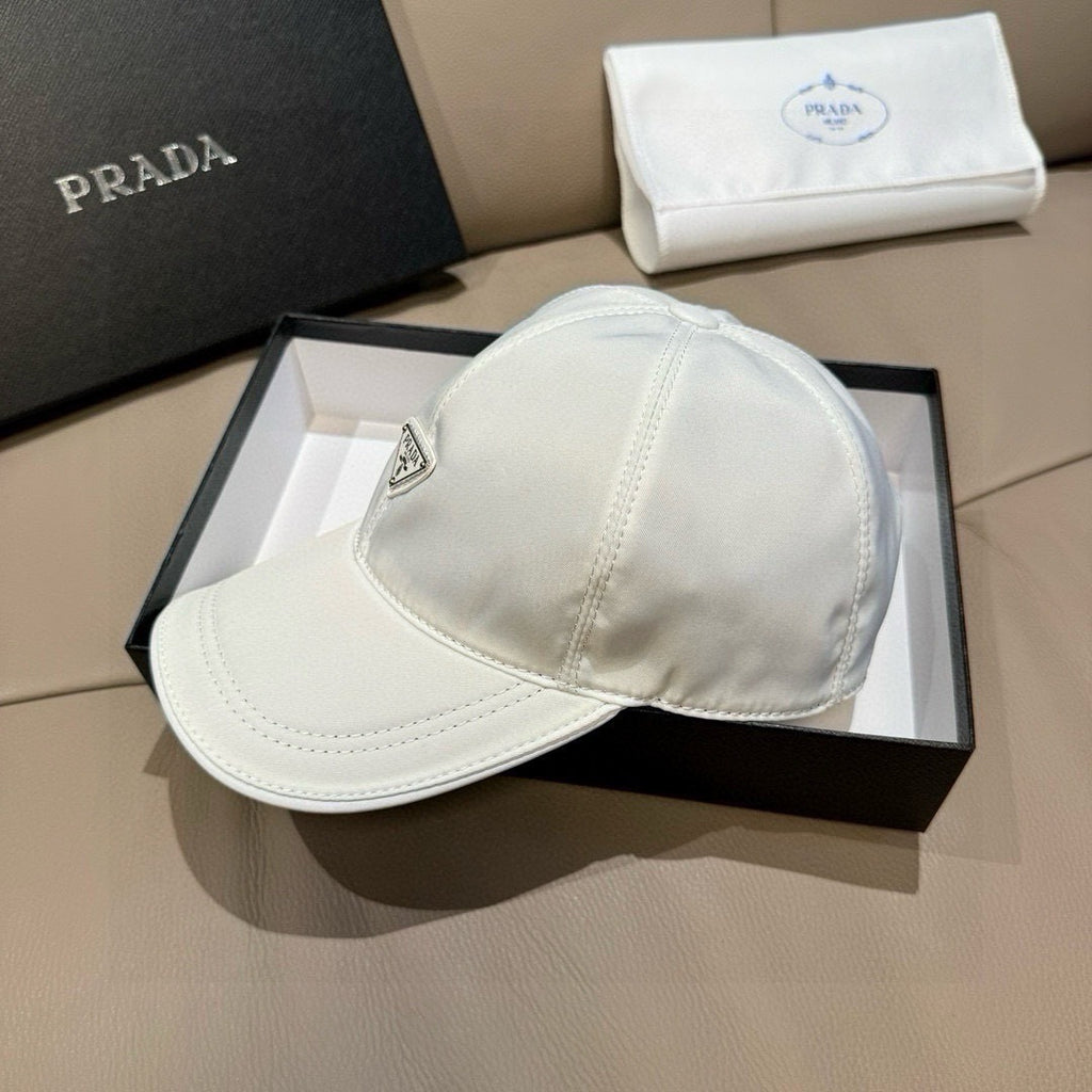 White baseball cap with Prada logo patch on side near adjustable strap.