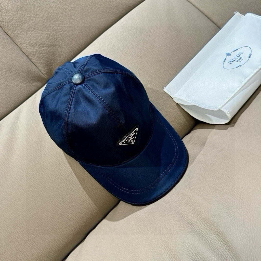 Prada dark blue baseball cap with round top button and logo patch on side.