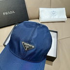 Prada baseball cap in dark blue satin fabric, triangular logo patch on front.