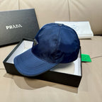 Prada dark blue baseball cap with curved brim and metal logo badge on front.