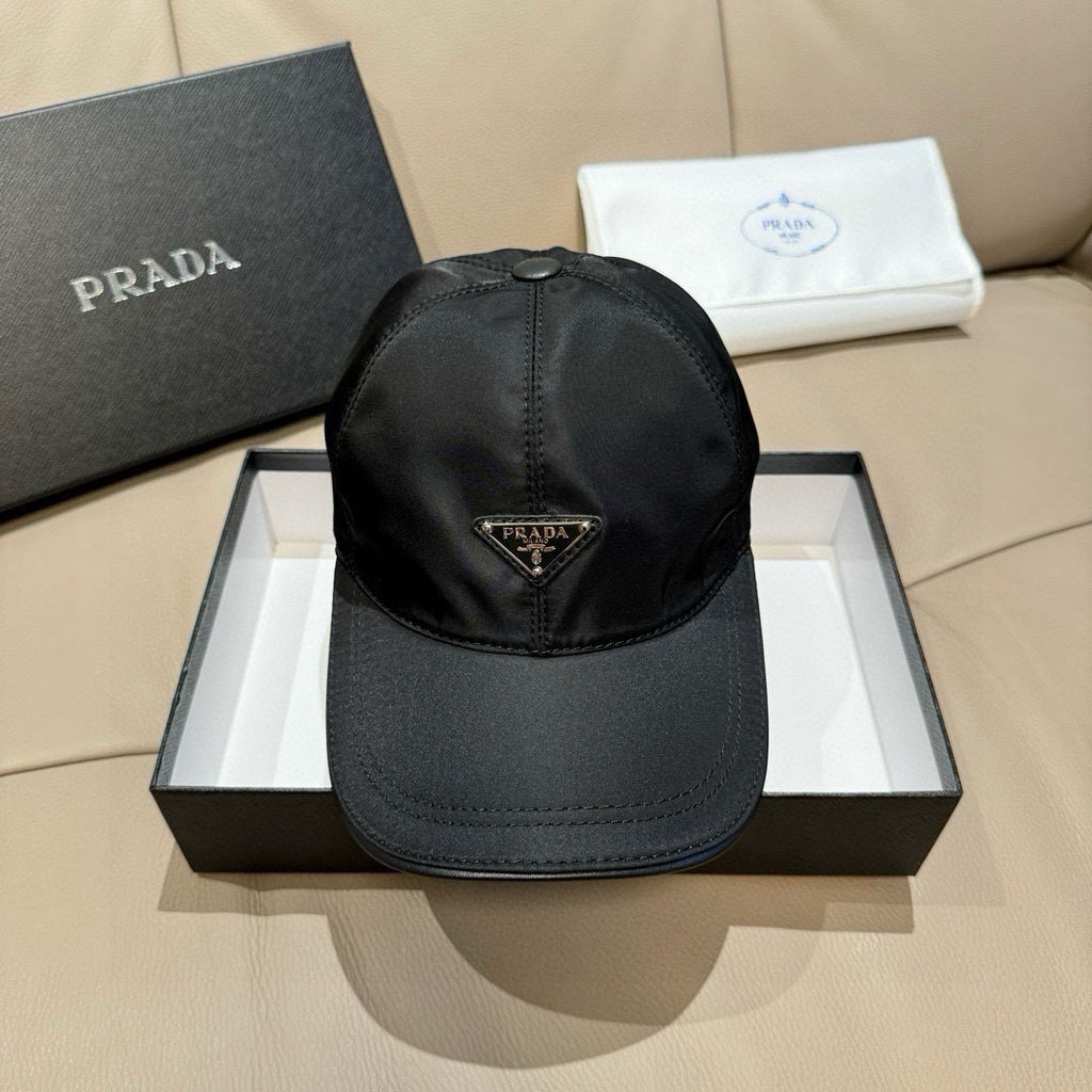 Black nylon baseball cap with Prada triangular logo patch, adjustable strap.