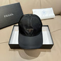Black nylon baseball cap with Prada triangular logo patch, adjustable strap.