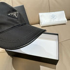 Black baseball cap brim with stitched edge and Prada triangular logo patch, close-up.
