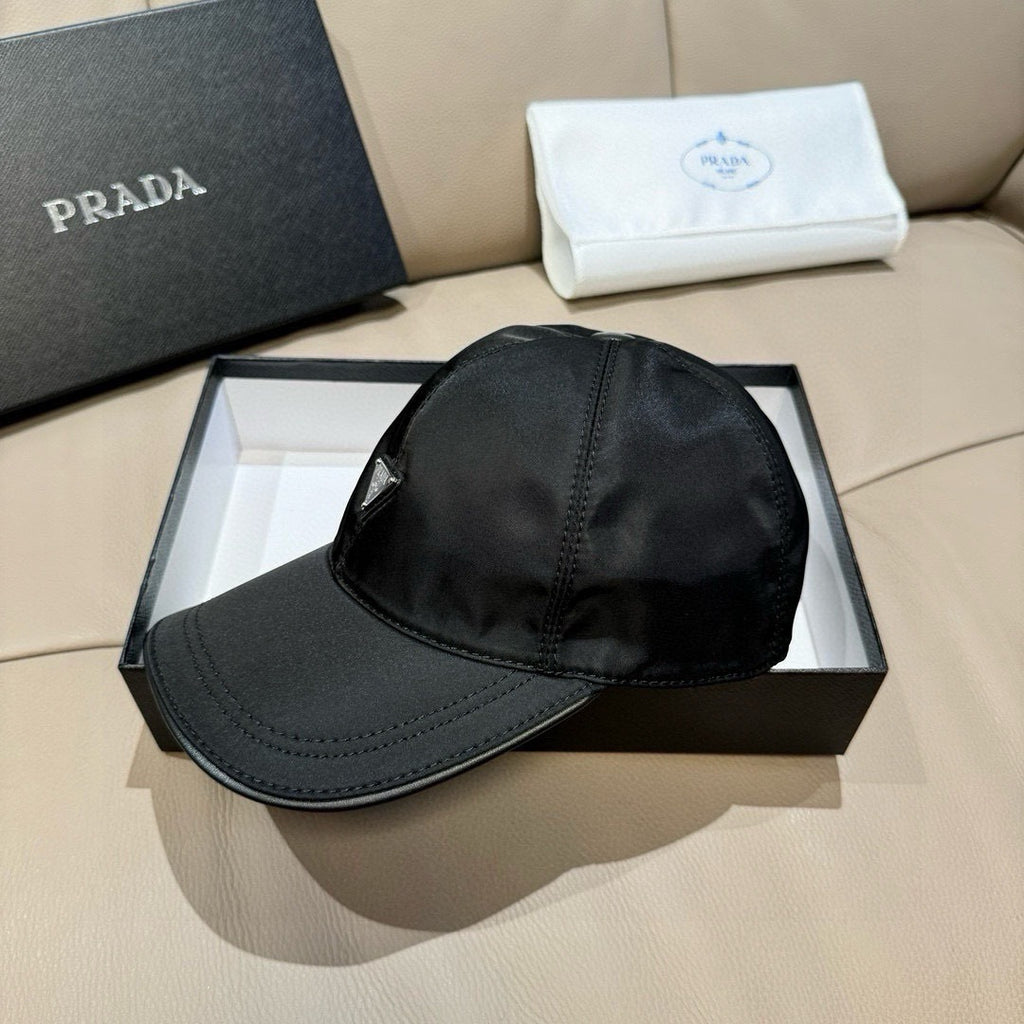 Black baseball cap with curved brim and Prada triangular logo patch on side.