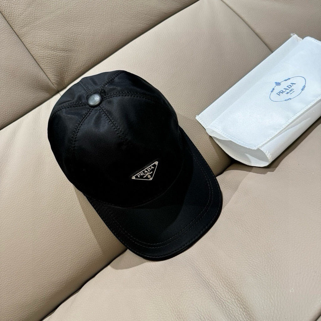 Black baseball cap with dome crown, metal button top, Prada triangular logo patch.