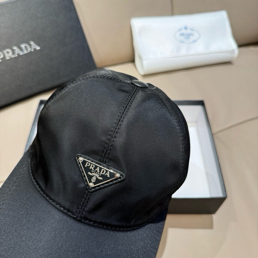 Black baseball cap with stitched crown seam and Prada triangular logo patch on side.