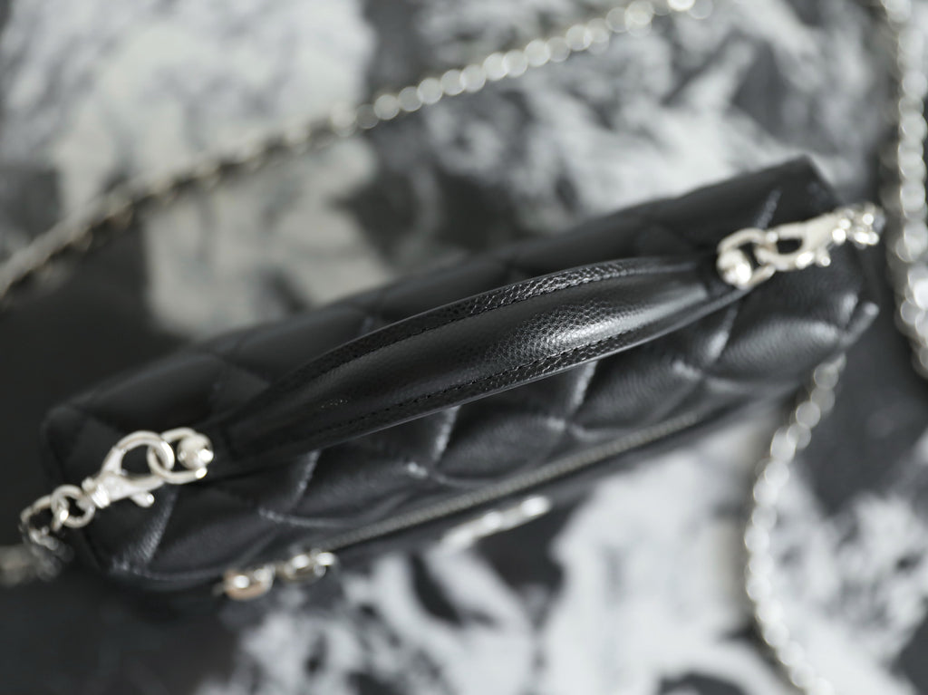 Close-up of chain strap and Chanel clasp on black quilted leather