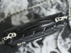Close-up of chain strap and Chanel clasp on black quilted leather