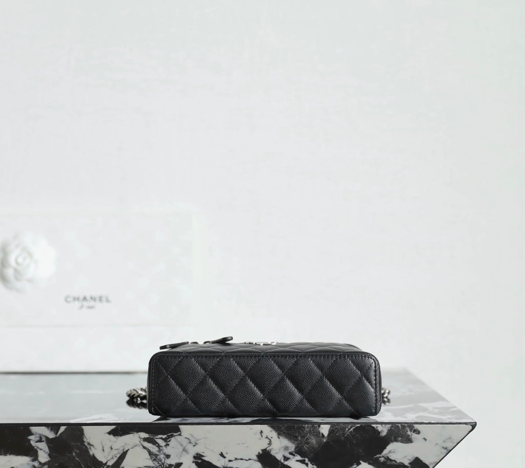 Chanel quilted handbag side view with chain strap and zipper top, black