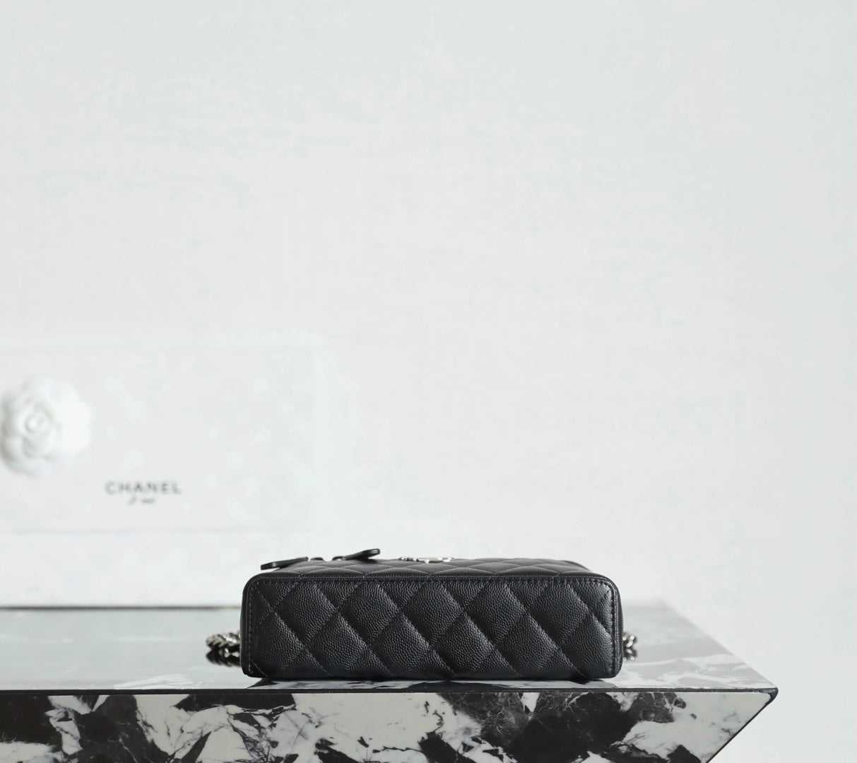 Chanel quilted handbag side view with chain strap and zipper top, black