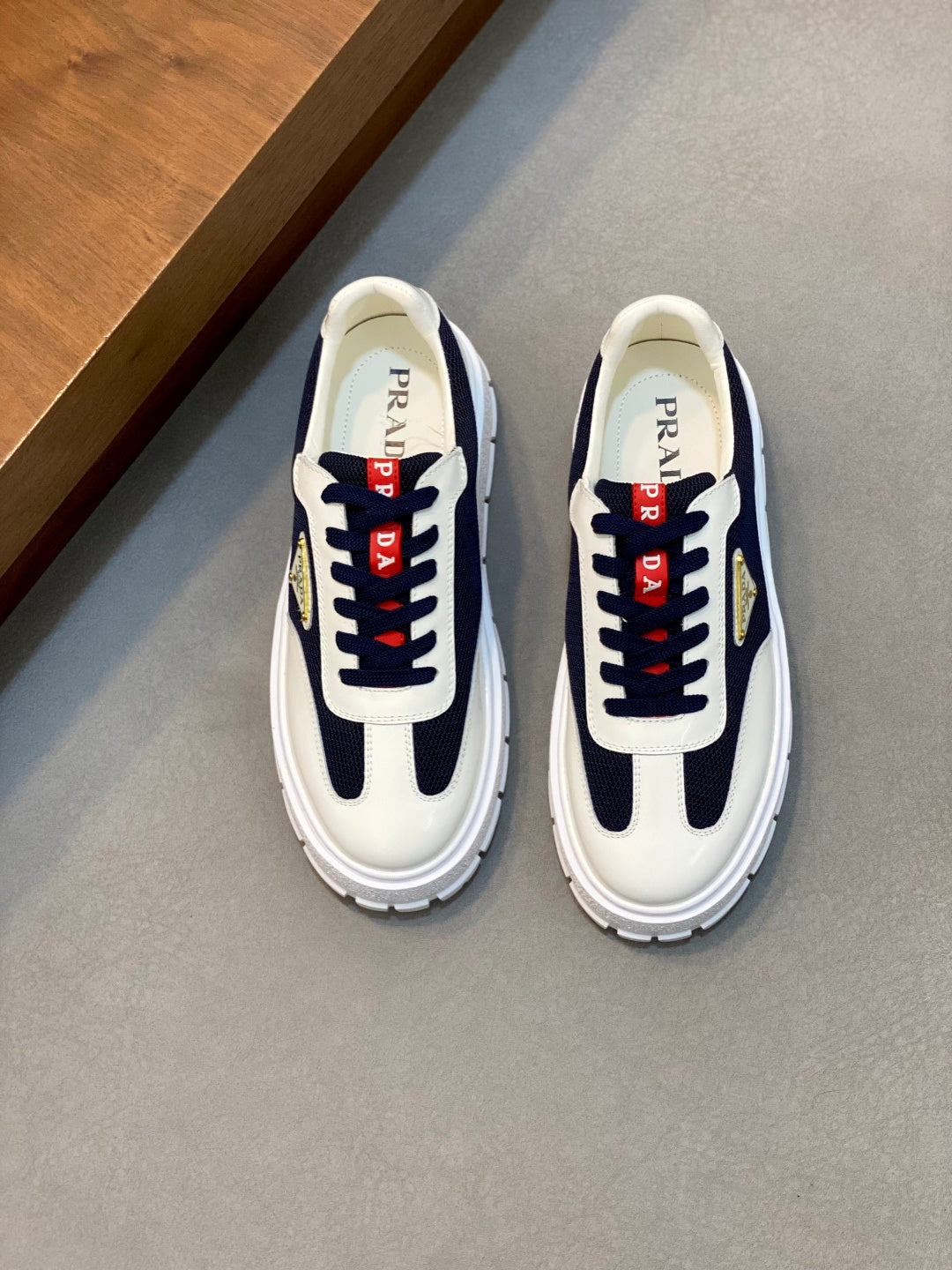 Unisex low-top sneakers in white and navy with red laces and gold logo detail