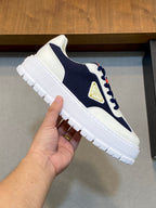 Unisex sneaker close-up in white and navy with red lace detail and gold triangular logo