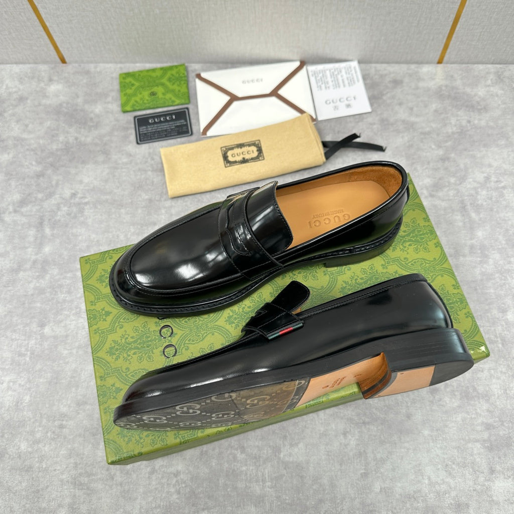 Unisex black leather loafers with strap detail and tan lining visible