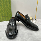 Unisex black leather loafers, angled front with glossy toe and strap
