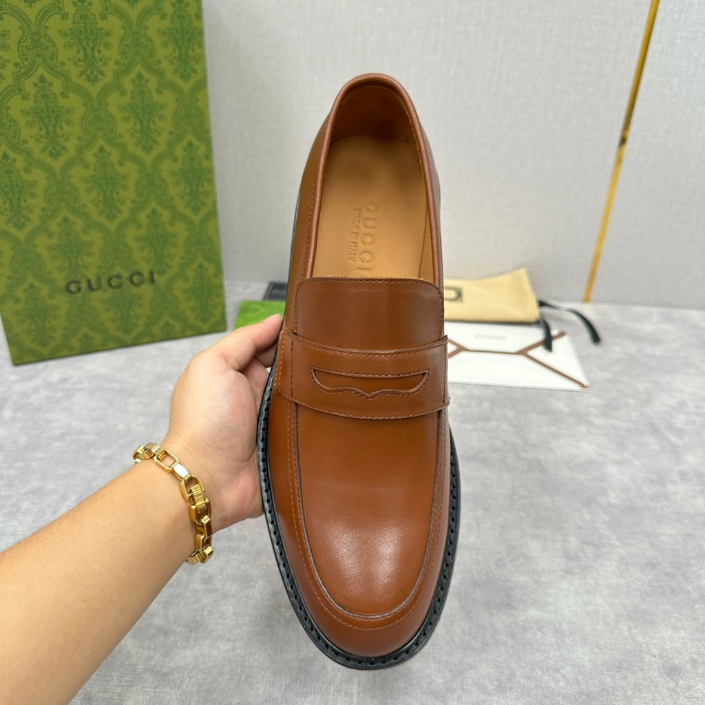 Brown leather loafer with penny strap, smooth vamp, and dark rubber sole