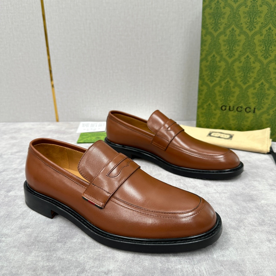 Brown leather loafer with stitched strap detail and black rubber sole
