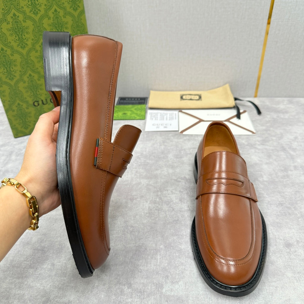 Brown leather Gucci loafer with penny strap, stitched seam, and rubber sole