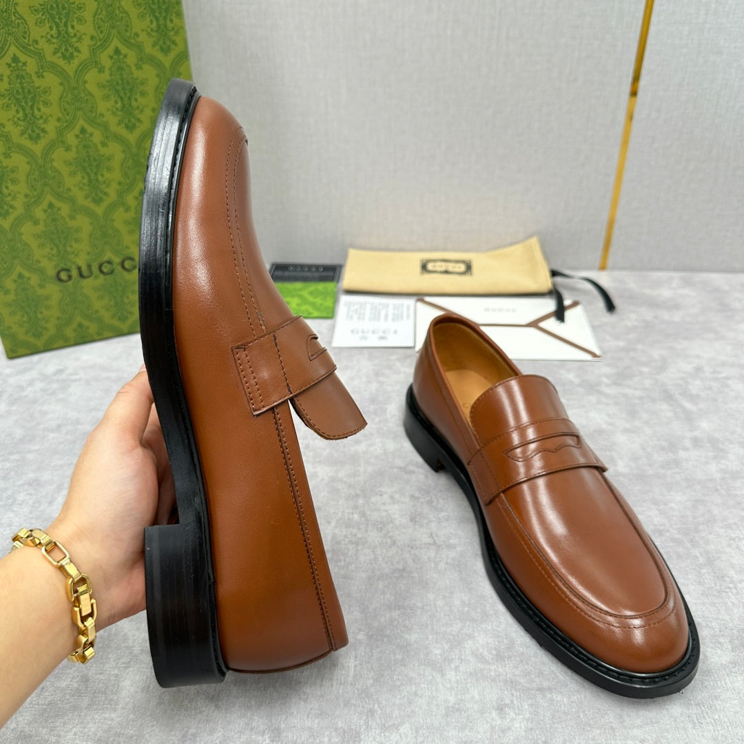 Brown leather loafer with penny strap, side stitching, and black rubber sole
