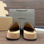 Black slip-on sandals with tan cork footbeds, front view showing open top