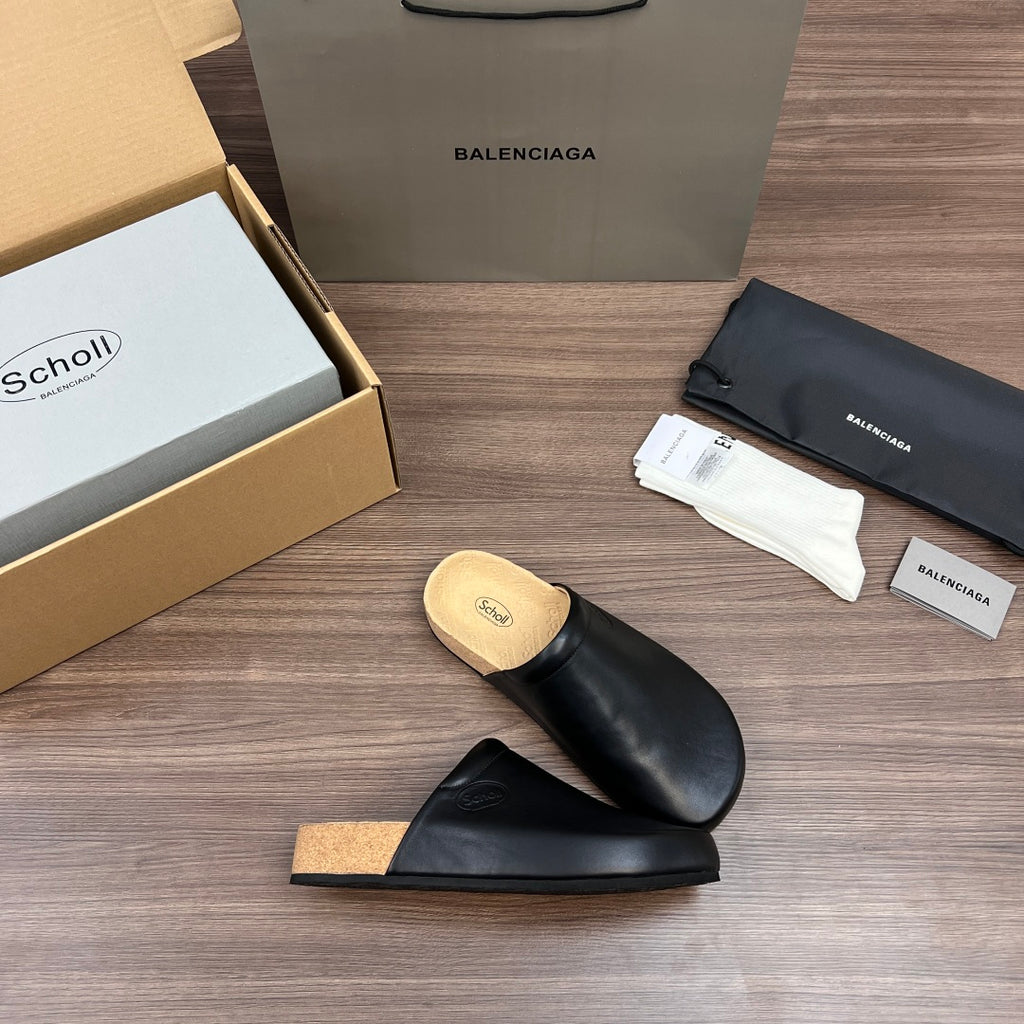 Black leather slide sandals with tan cork footbed and smooth strap across top
