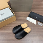 Black leather slide sandals with tan cork footbed, side angle view
