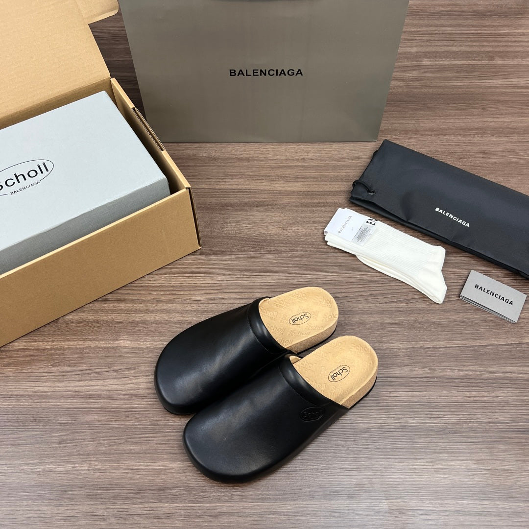 Black leather slide sandals with tan cork footbed, side angle view