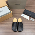 Black leather slide sandals with tan cork footbed, slip-on style