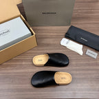 Black leather slide sandal with tan cork sole, showing top and side angles