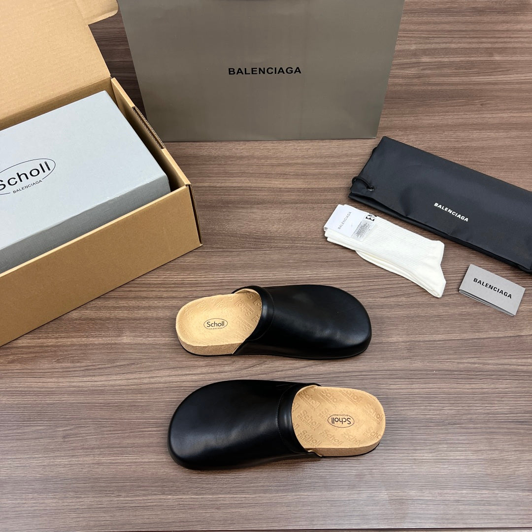 Black leather slide sandal with tan cork sole, showing top and side angles